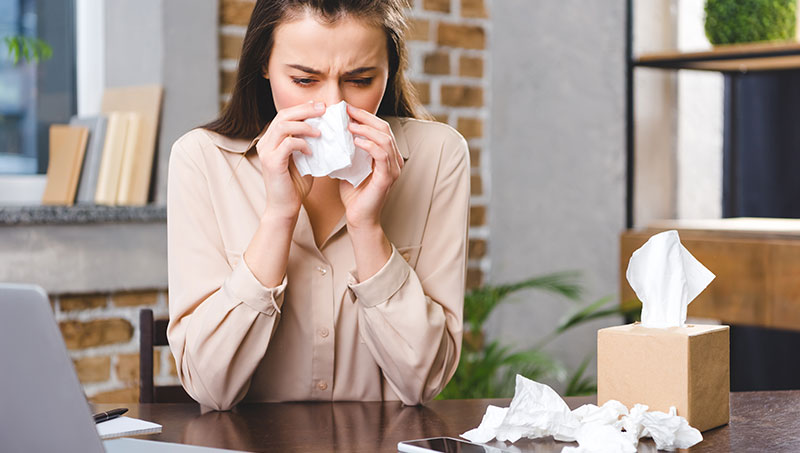 Woman suffering from horrible alergies at work