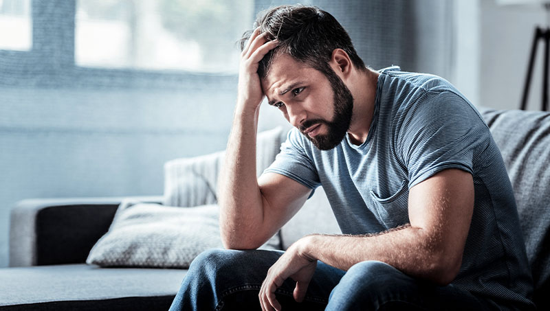 Man sitting on couch dealing with stress at home